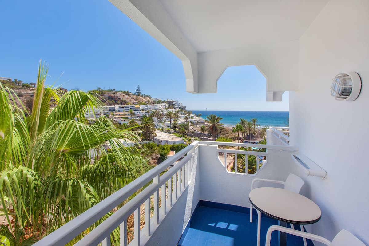 A balcony with a view of the sea and a white railing.