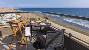 Una terraza con una mesa lista para el desayuno con vista a la playa.