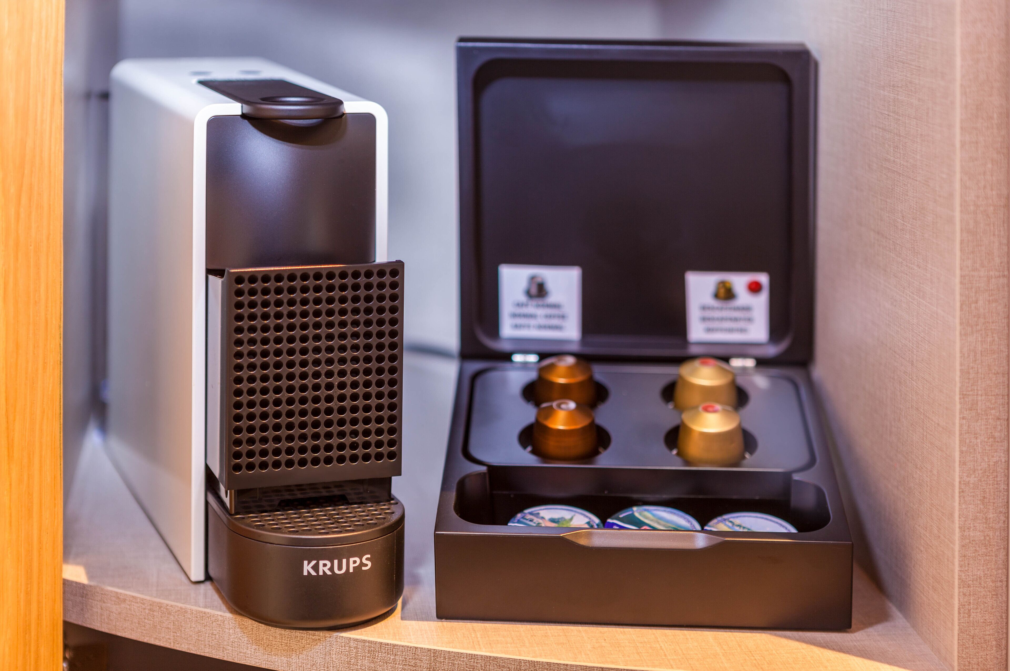 A coffee machine with a Krups brand, a coffee pod holder, and two coffee pods.
