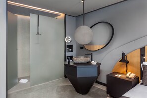 A modern bathroom with a large round mirror, a vessel sink, and a bedside table with a lamp and phone. - Hotel Faro, a Lopesan Collection Hotel - Adults Only (San Bartolomé de Tirajana)
