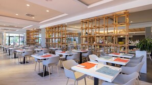 A spacious library with multiple tables and chairs, wooden bookshelves, and a modern ceiling design. - Abora Continental by Lopesan Hotels - All Inclusive (San Bartolomé de Tirajana)