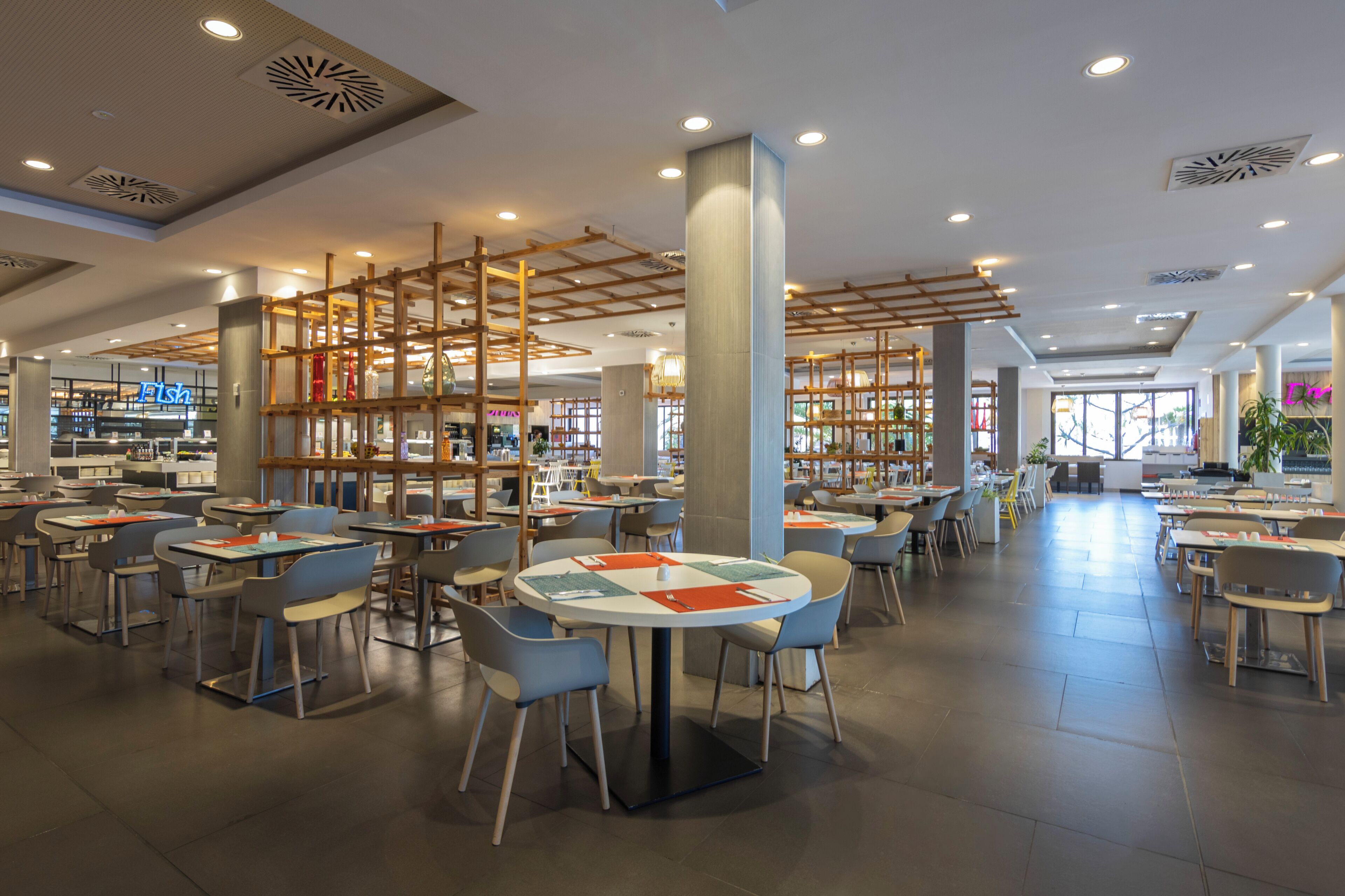 Un restaurant moderne avec des tables rondes, des chaises et une cloison en bois.
