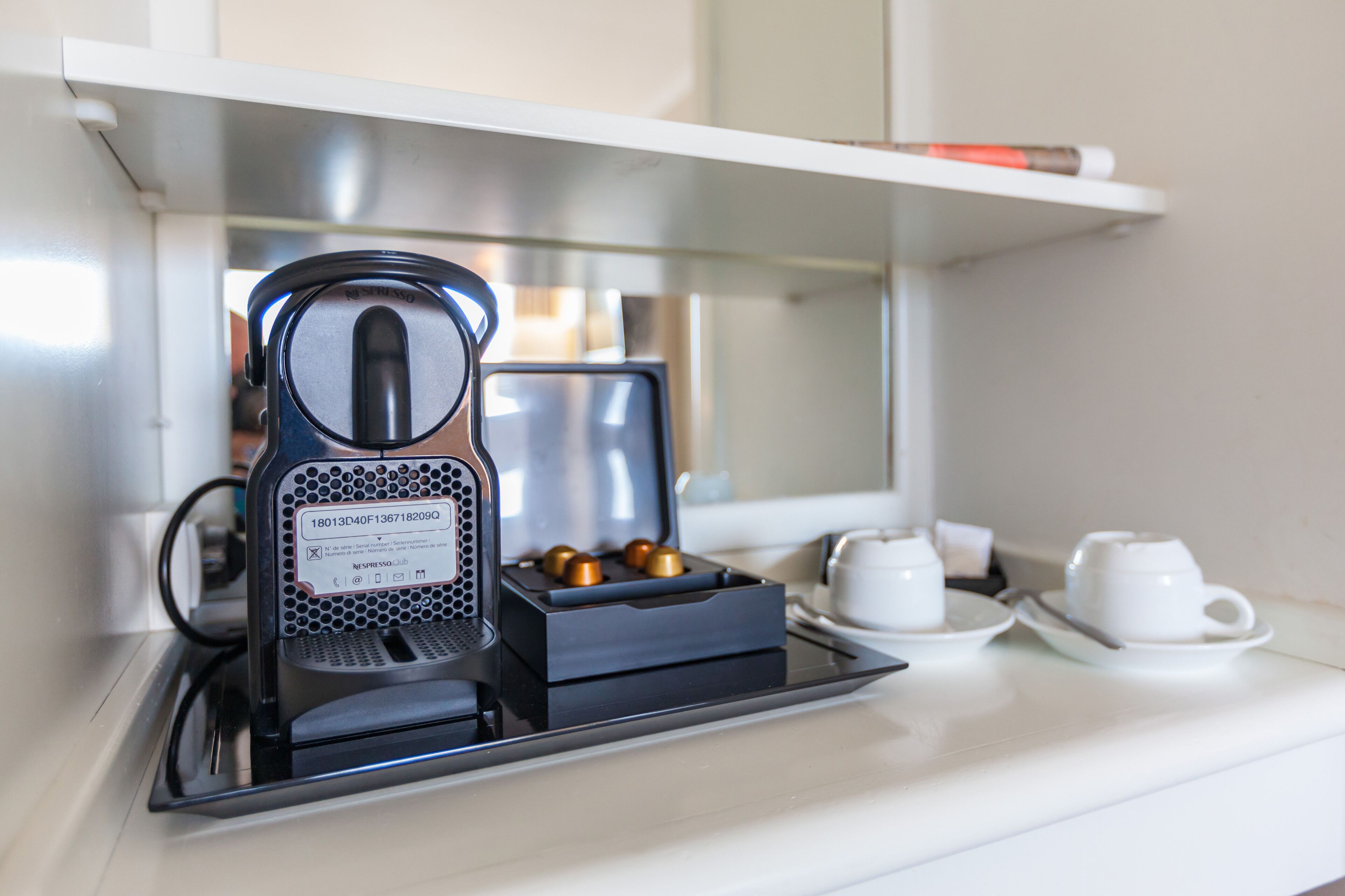 A coffee maker on a counter with a tray, a cup, and a saucer.