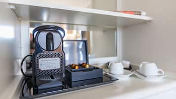 A coffee maker on a counter with a tray, a cup, and a saucer.
