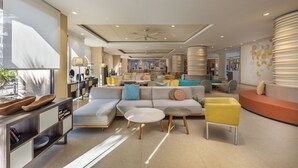 A modern interior with a sectional sofa, round coffee tables, and a yellow armchair. - Abora Continental by Lopesan Hotels - All Inclusive (San Bartolomé de Tirajana)