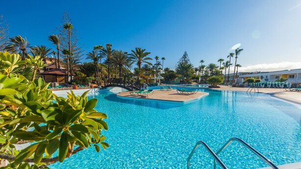 A swimming pool with clear blue water, surrounded by palm trees and lounge chairs. - Abora Interclub Atlantic by Lopesan Hotels - All inclusive (San Bartolomé de Tirajana)