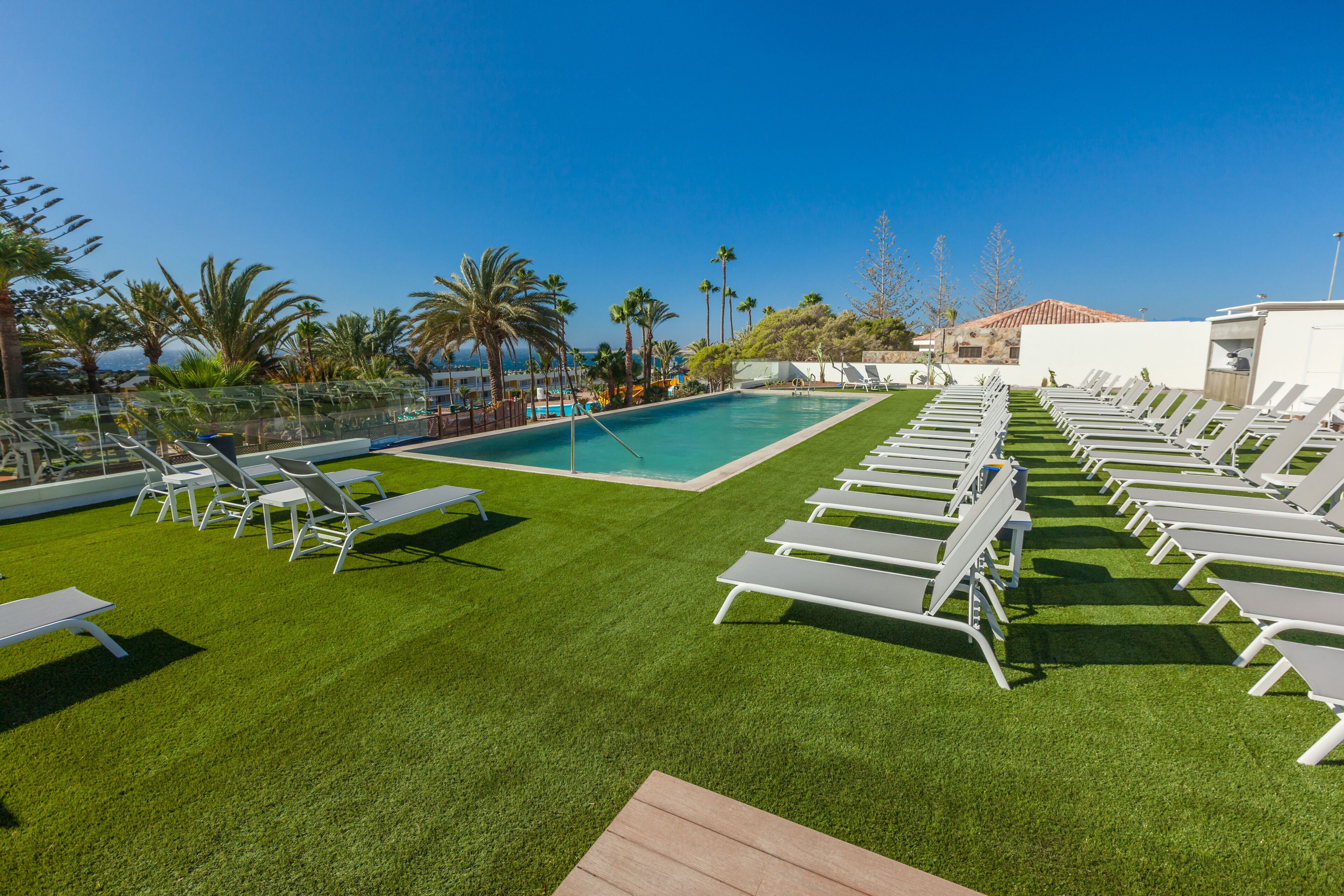 Un espace aménagé au bord de la piscine, avec des chaises longues blanches et une piscine.