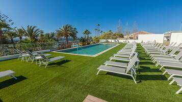 Un espace aménagé au bord de la piscine, avec des chaises longues blanches et une piscine.