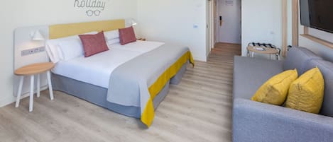 A modern hotel room with a bed, a bedside table, a chair, a sofa, and a TV.