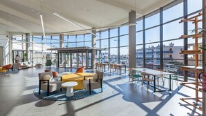 A spacious indoor area with large windows, a central seating area with sofas and tables, and a view of the cityscape outside. - Abora Interclub Atlantic by Lopesan Hotels - All inclusive (San Bartolomé de Tirajana)