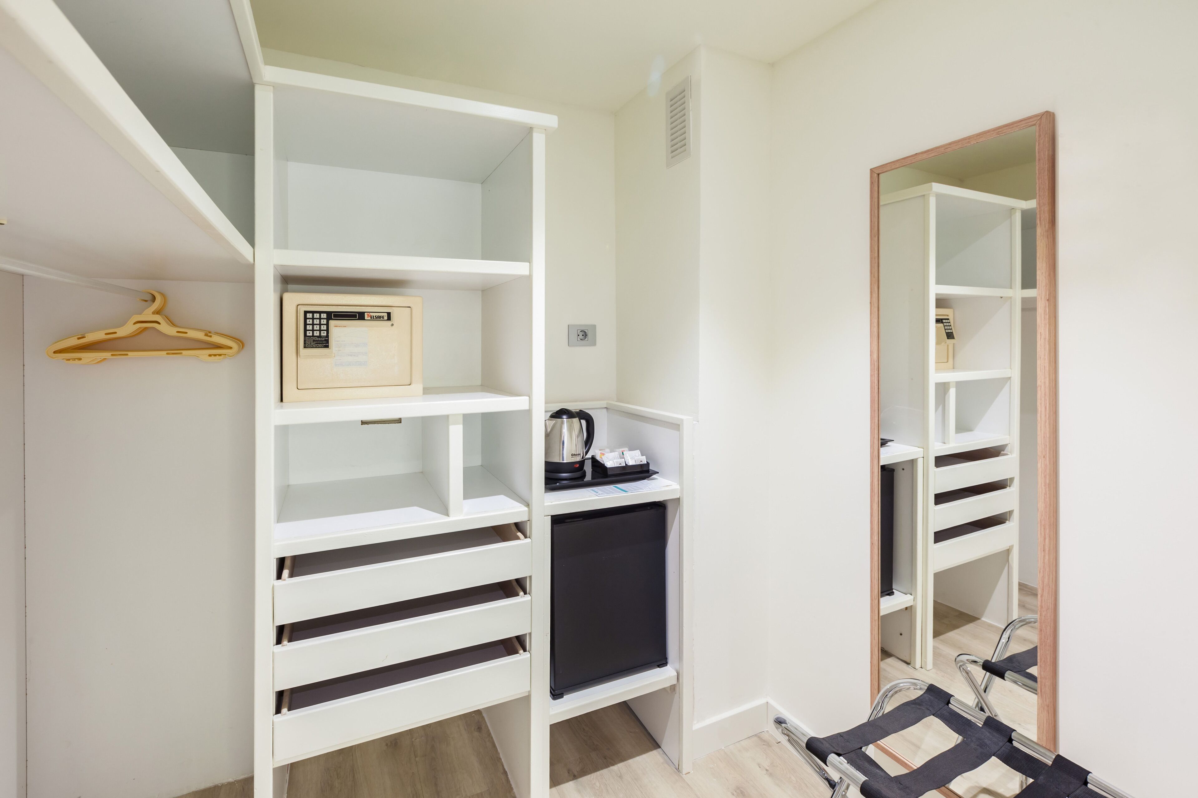 A white closet with shelves, a hanging rack, and a small black appliance.