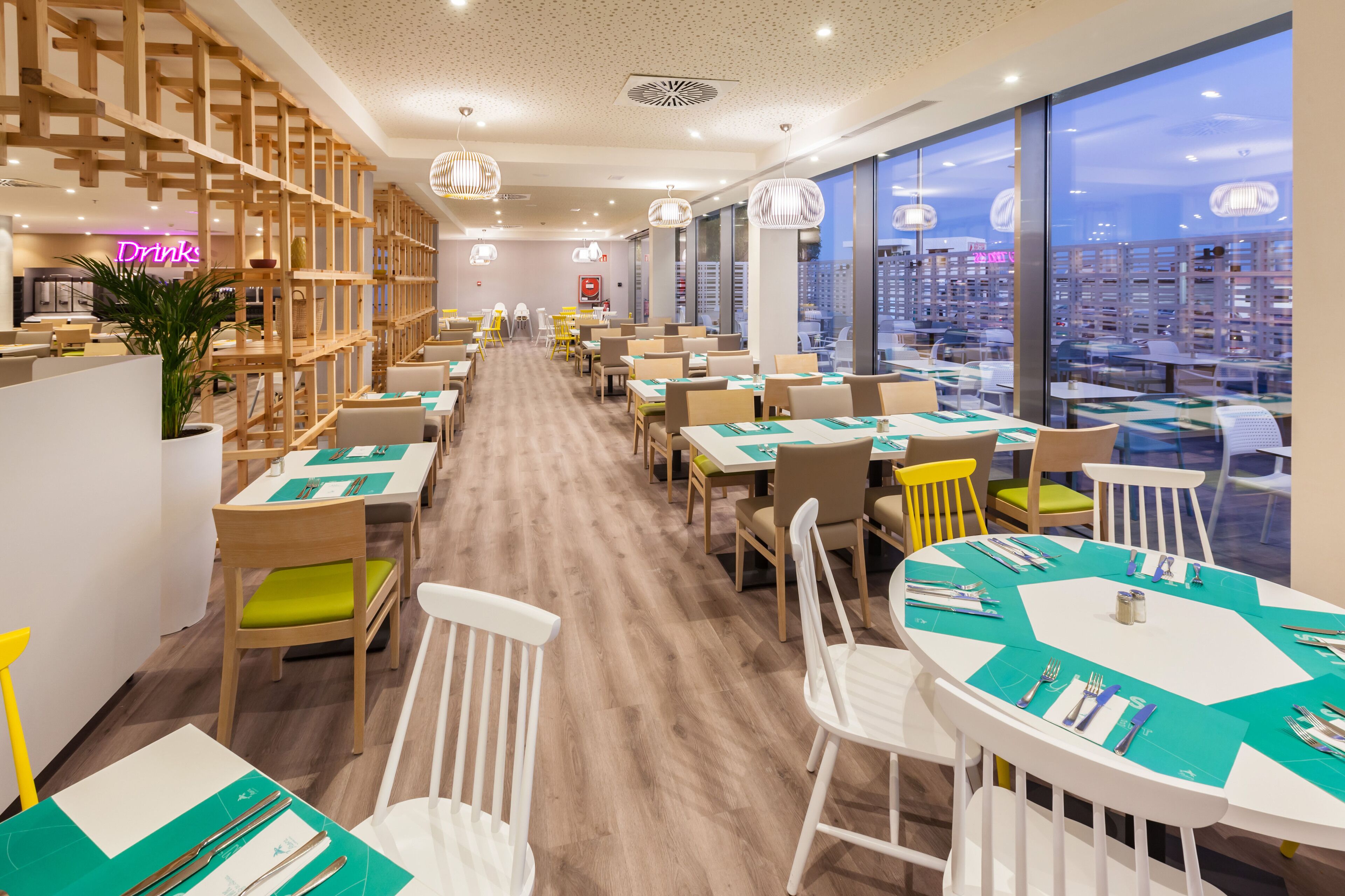 A modern restaurant with a long counter, wooden partitions, and a city view.