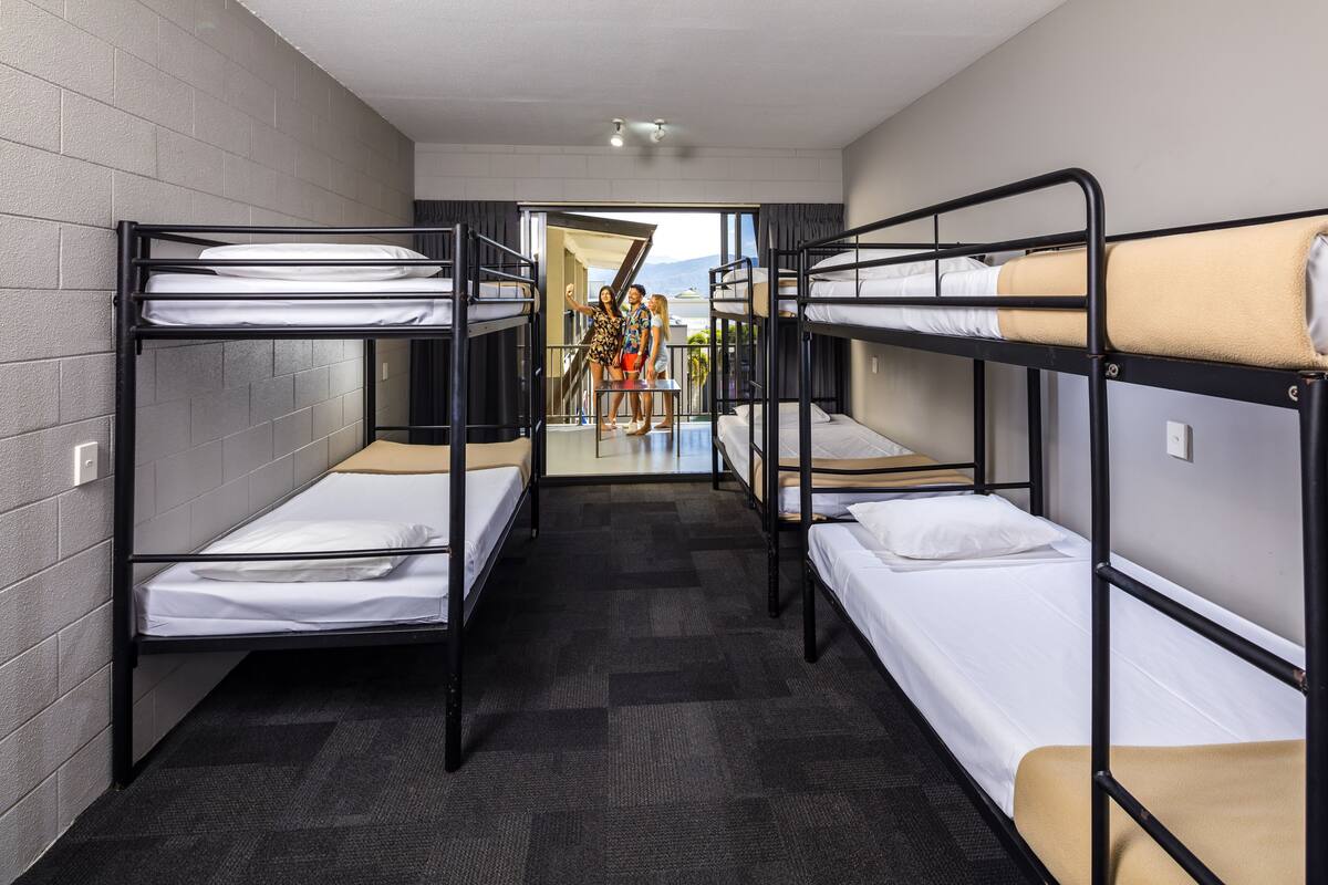 A room with bunk beds, a carpeted floor, and a view through an open door.
