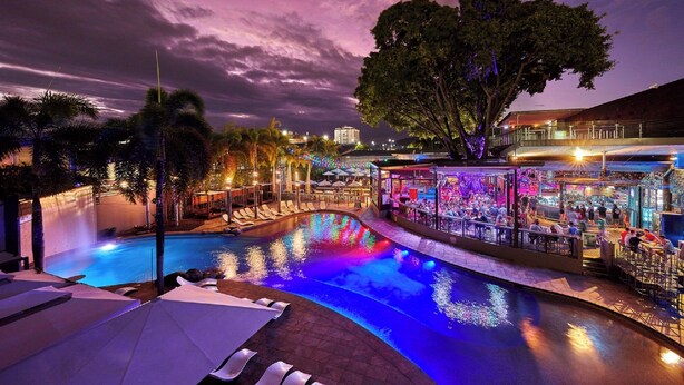 A pool area with lounge chairs and a bar area with umbrellas.