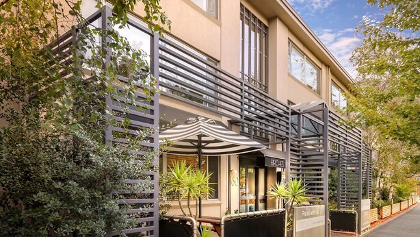A modern building with a balcony, outdoor seating area, and a sign for 'Birches'. - Birches Serviced Apartments (East Melbourne)