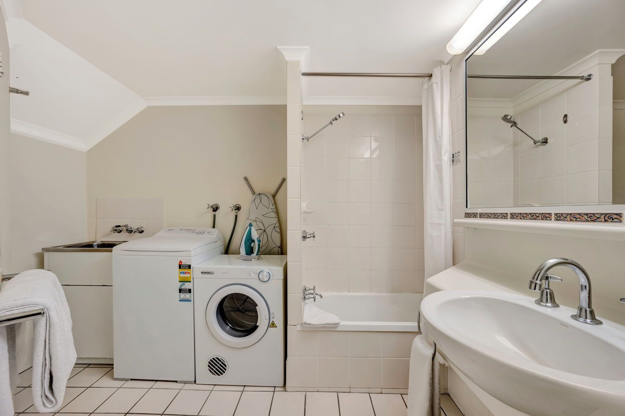 Een kleine badkamer met een wasmachine, een bad en een wastafel.