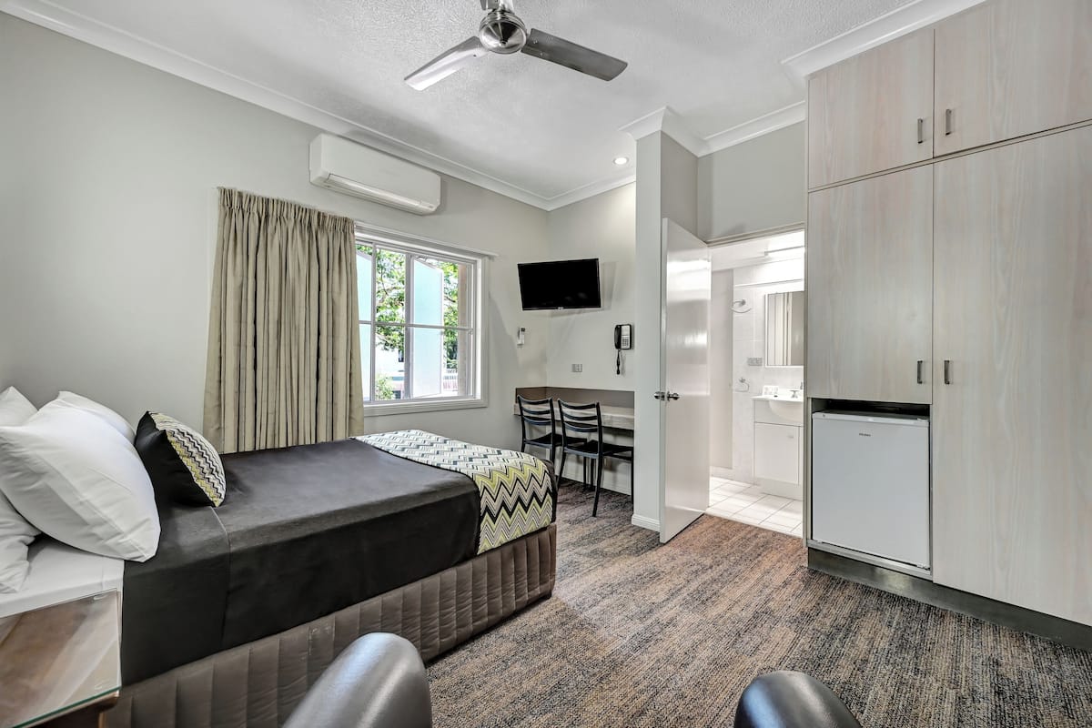 Une chambre à coucher comprenant un lit, un bureau, une chaise, une télévision et une armoire.