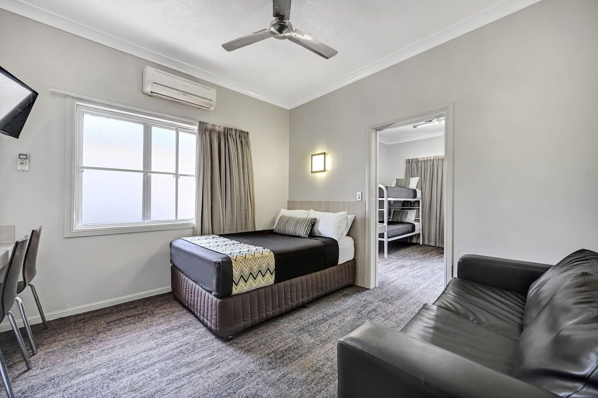 Une chambre d’hôtel équipée d’un lit, d’un canapé, d’un bureau et d’un ventilateur de plafond.