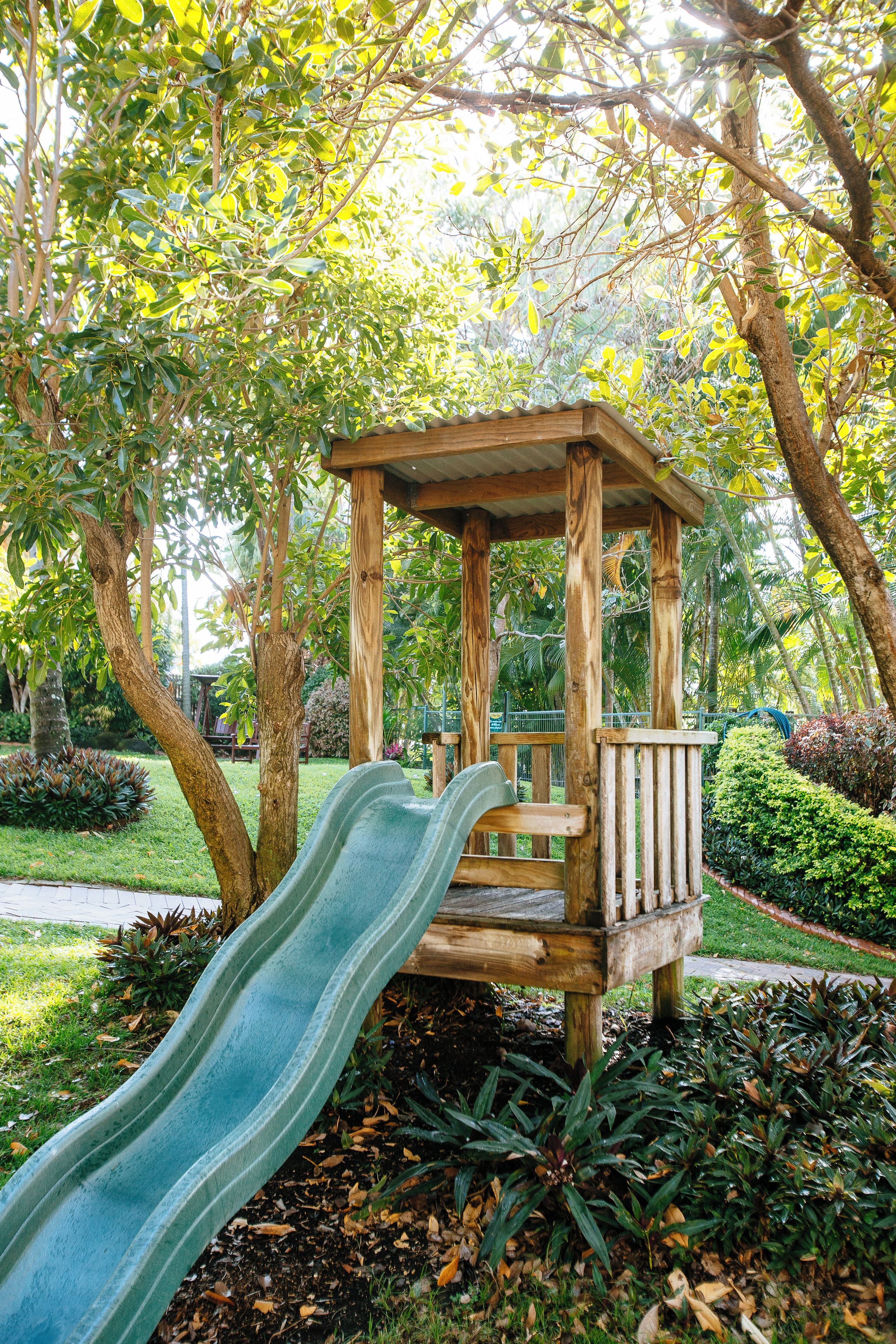 A wooden play structure with a slide in a park.