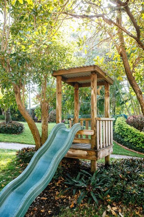 Une structure de jeux en bois avec un toboggan, installée dans un parc.