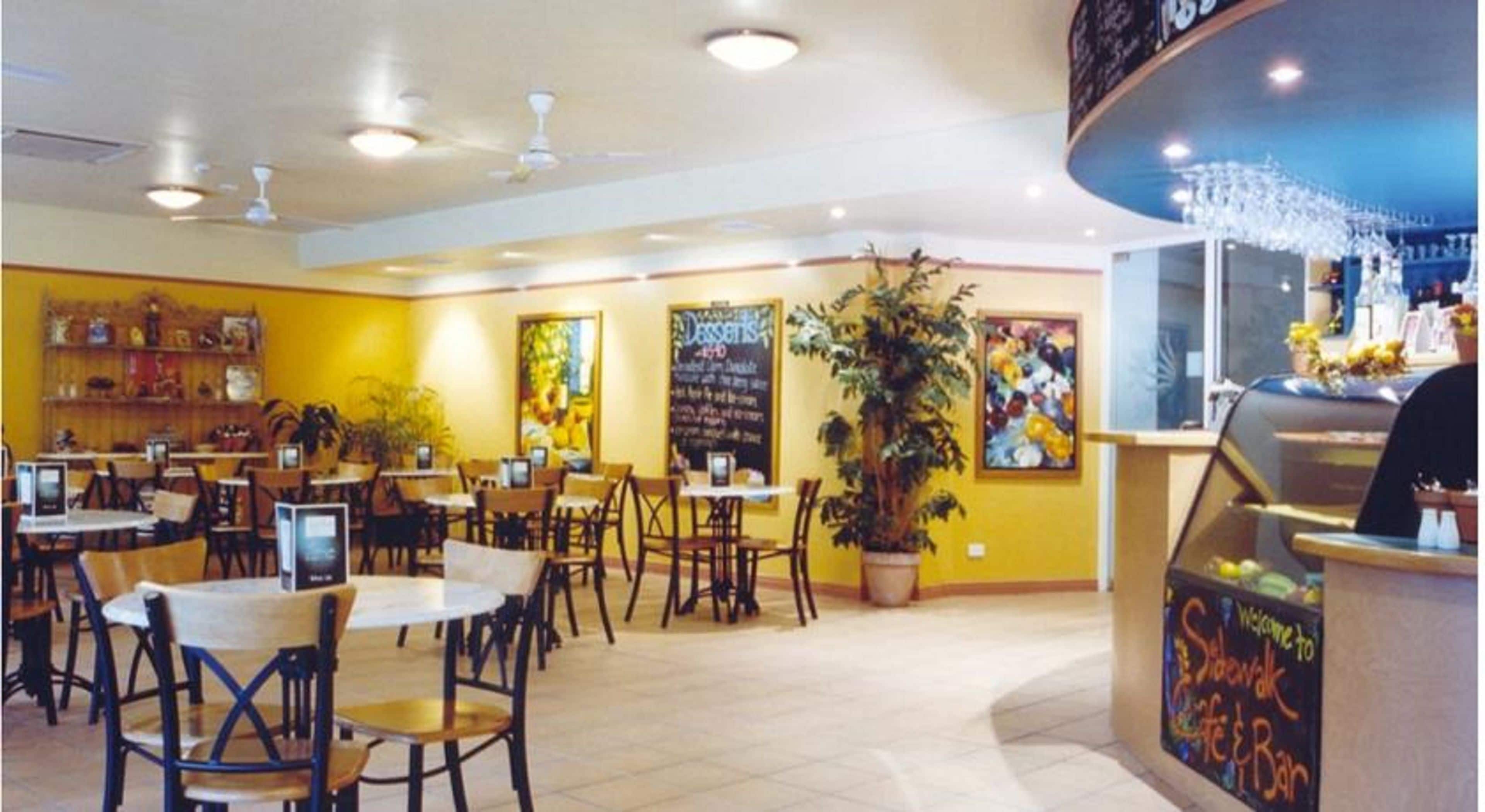 A restaurant interior with multiple tables and chairs, a chalkboard menu, and a bar area.