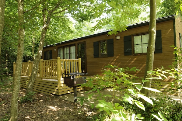 Guests can enjoy a peaceful retreat in this cabin surrounded by a dense forest, featuring a spacious deck with a railing.