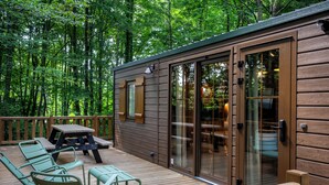 A wooden deck with outdoor furniture, a picnic table, and a glass door leading to an interior space. - Disney Davy Crockett Ranch (Bailly-Romainvilliers)