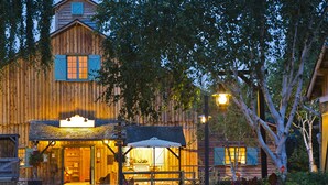 A rustic wooden building with a welcoming entrance, a covered outdoor seating area, and a well-maintained garden. - Disney Davy Crockett Ranch (Bailly-Romainvilliers)