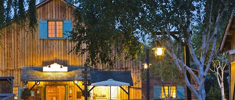 A rustic wooden building with a welcoming entrance, a covered outdoor seating area, and a well-maintained garden.