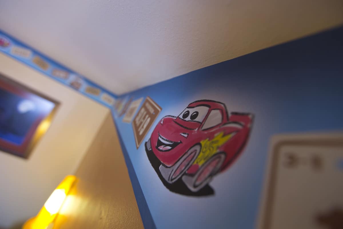 A wall with a cartoon car character and a framed picture.