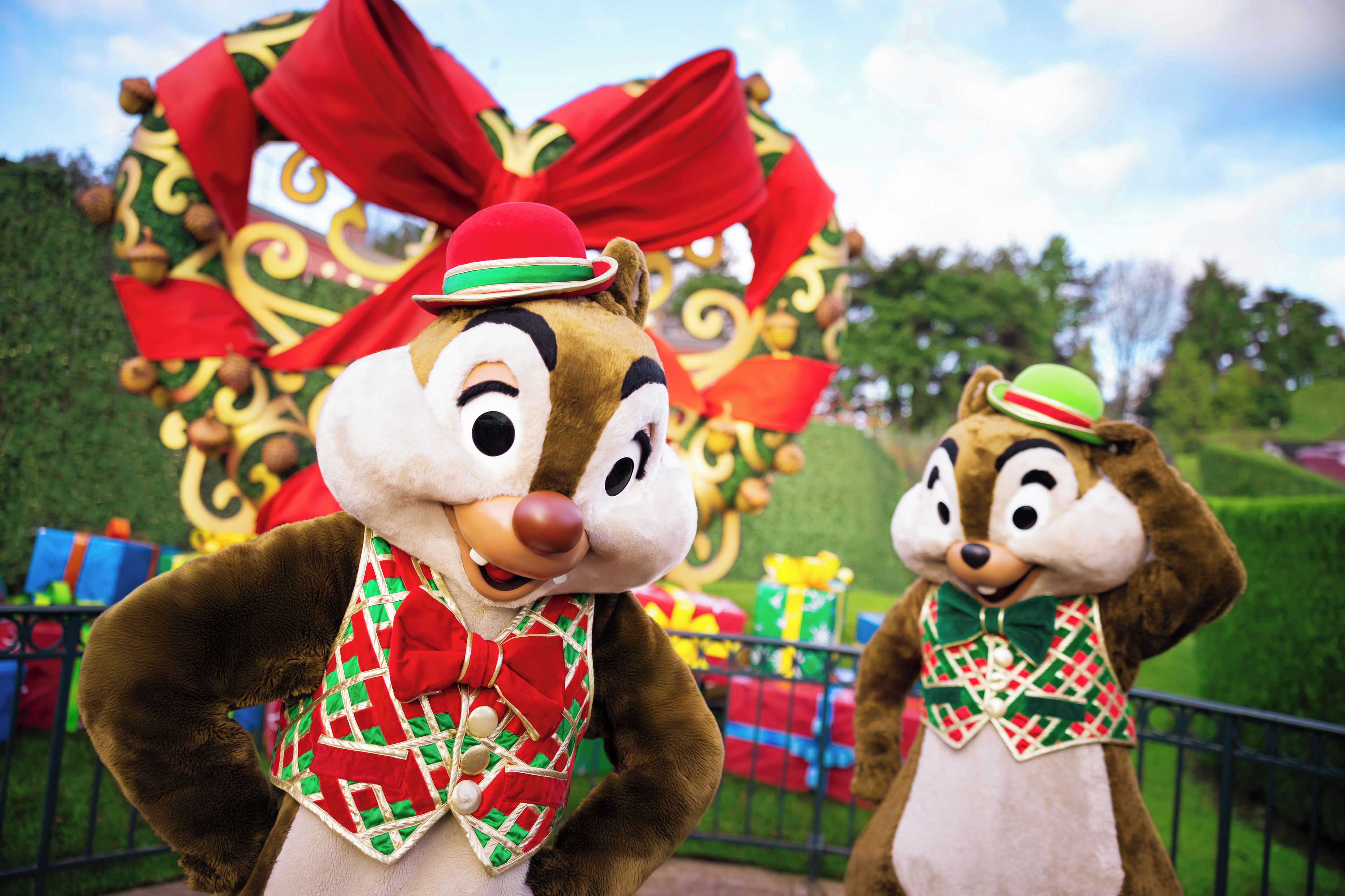 Two characters in festive costumes with a large decorative backdrop.