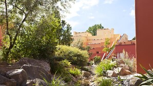 A garden with a small stream, rocks, and various plants. There are buildings in the background. - Disney Hotel Santa Fe (Coupvray)