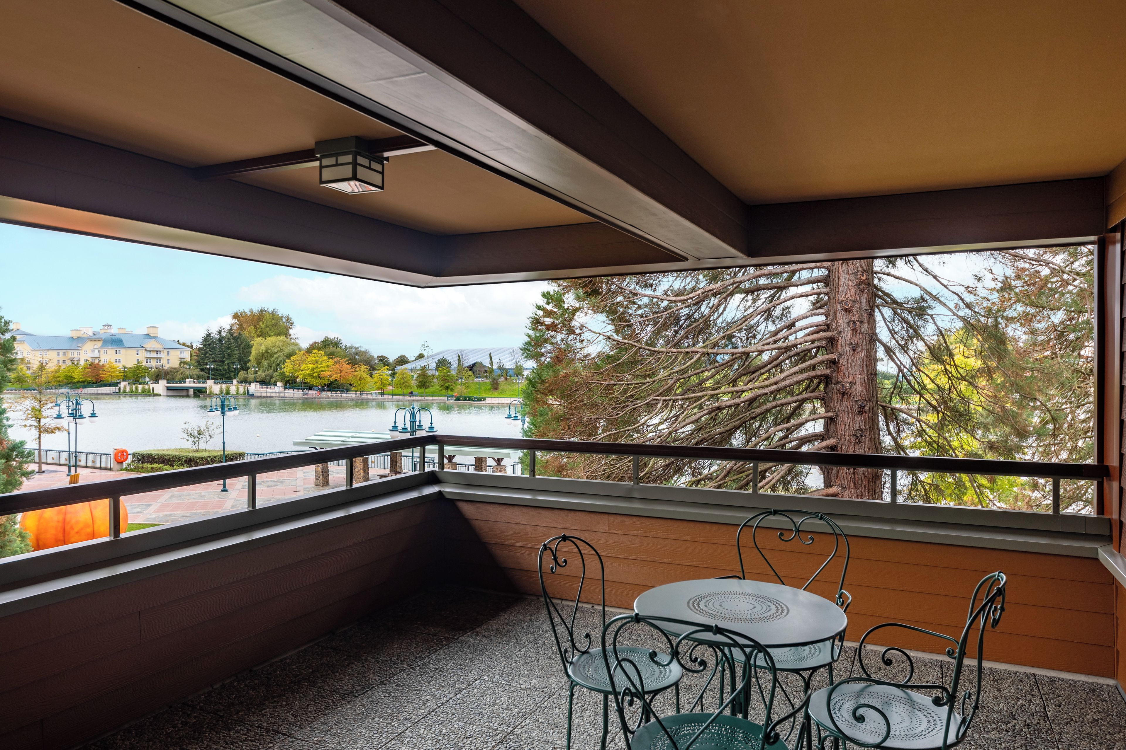 A balcony with a view of a lake, trees, and a distant building.