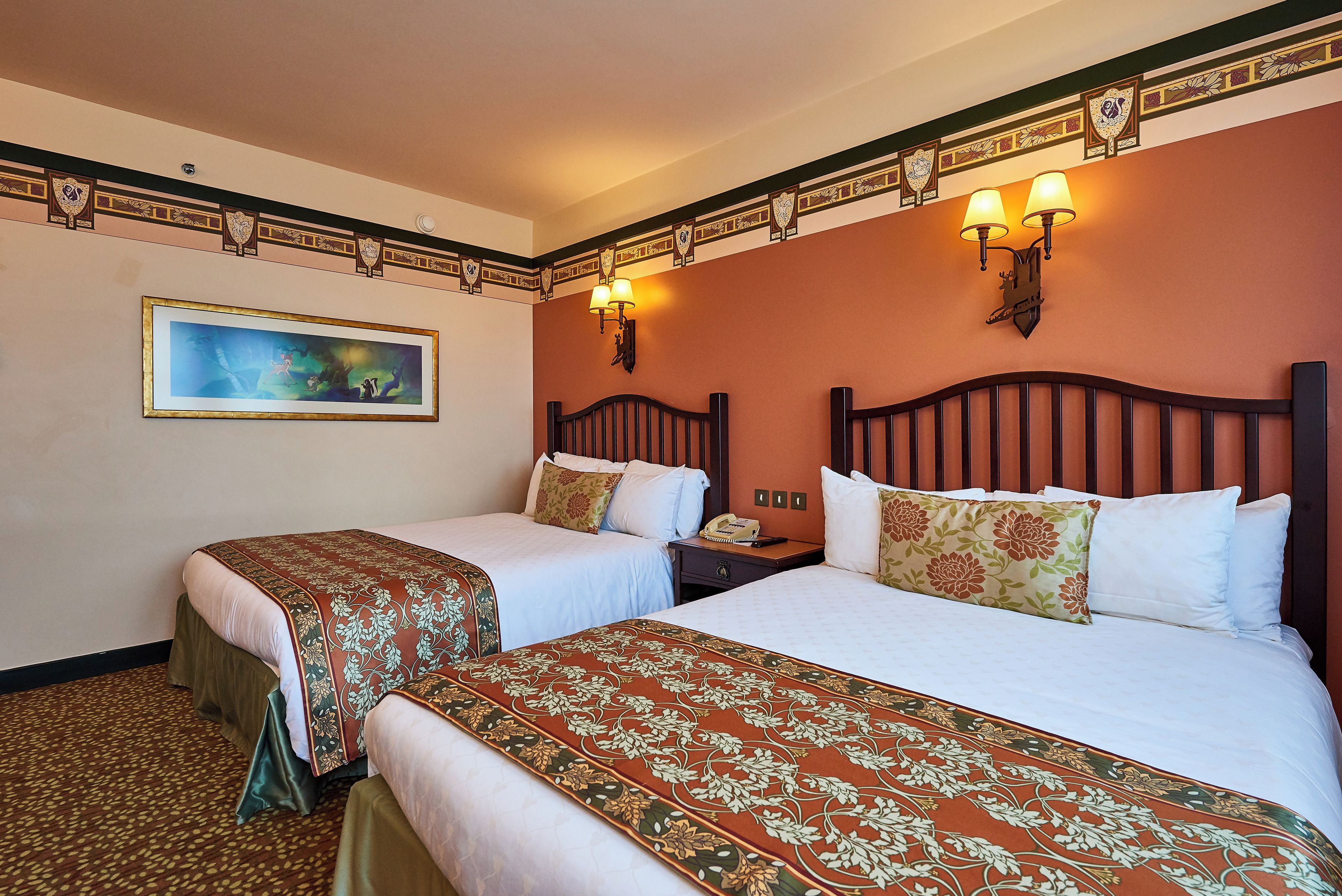 A hotel room with two beds, a nightstand, a telephone, and a framed picture on the wall.