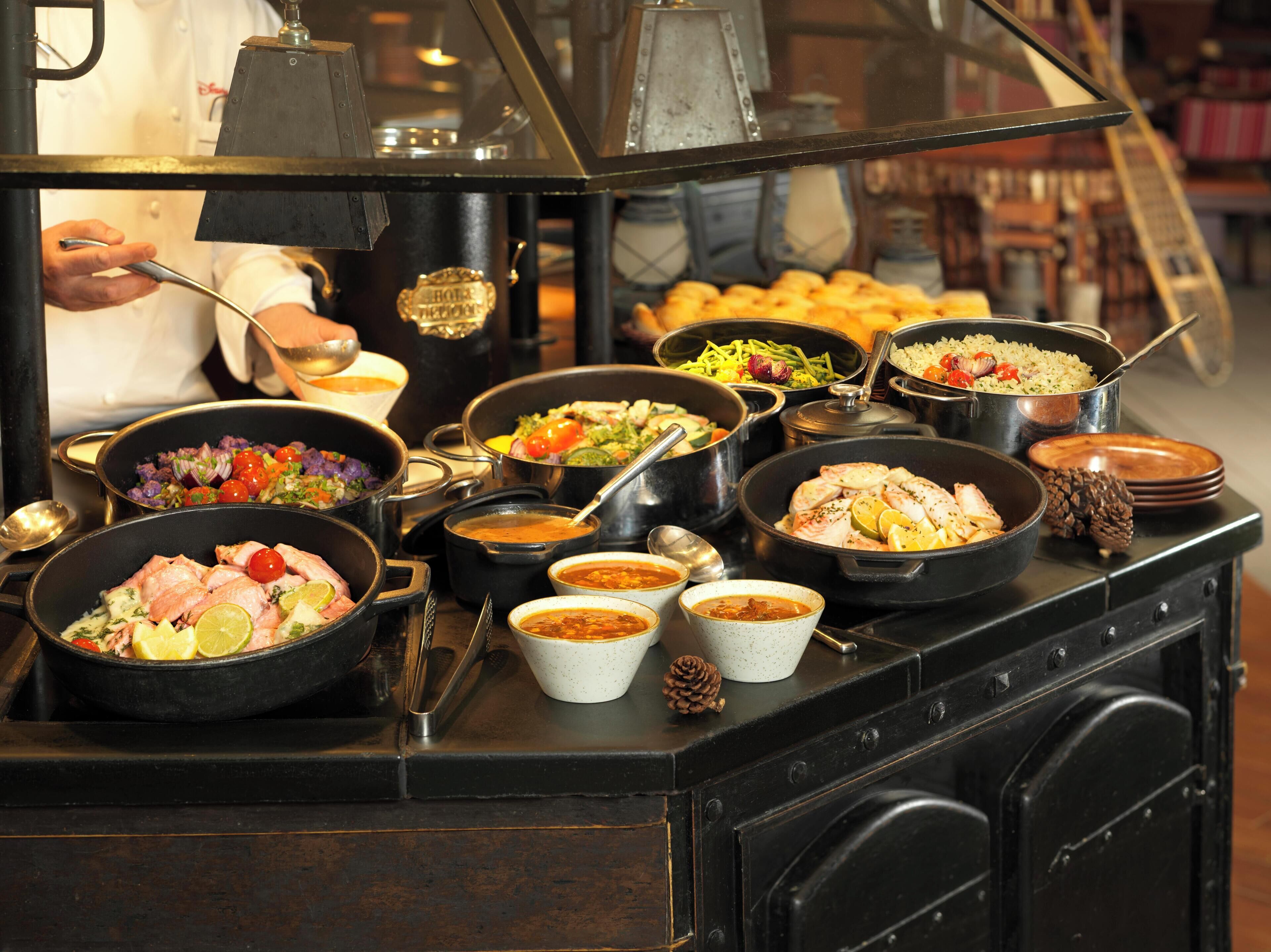 Un bufé con diversos platos, entre ellos mariscos, ensaladas y arroz.