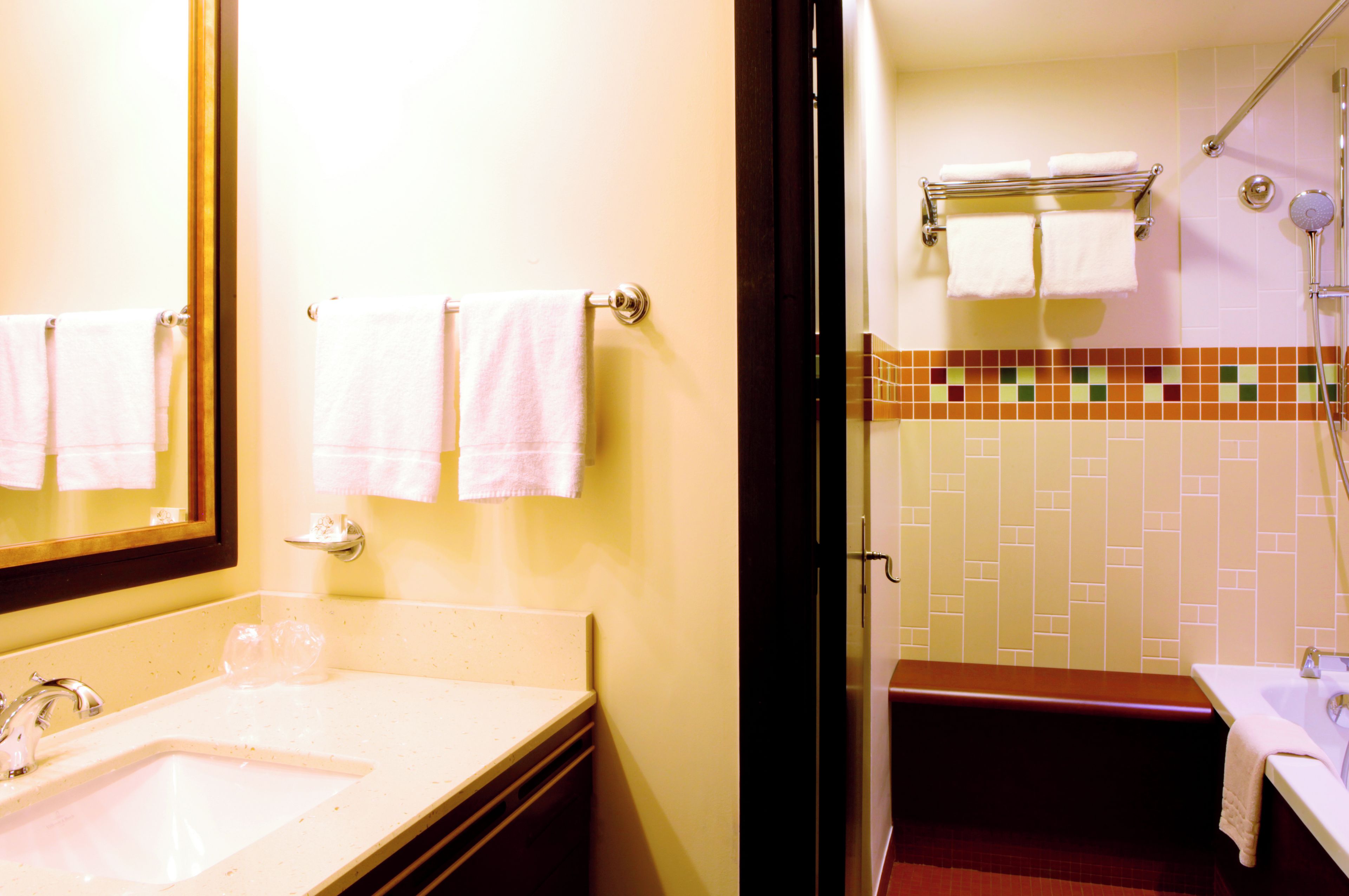 A bathroom with a sink, mirror, and shower area.