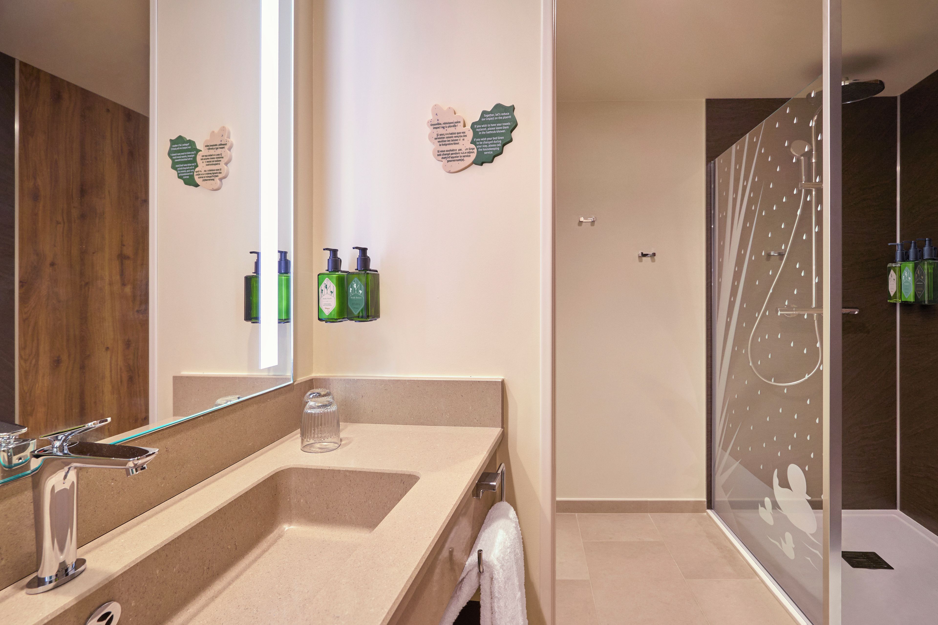 A modern bathroom with a large mirror, a sink, and a glass shower enclosure.
