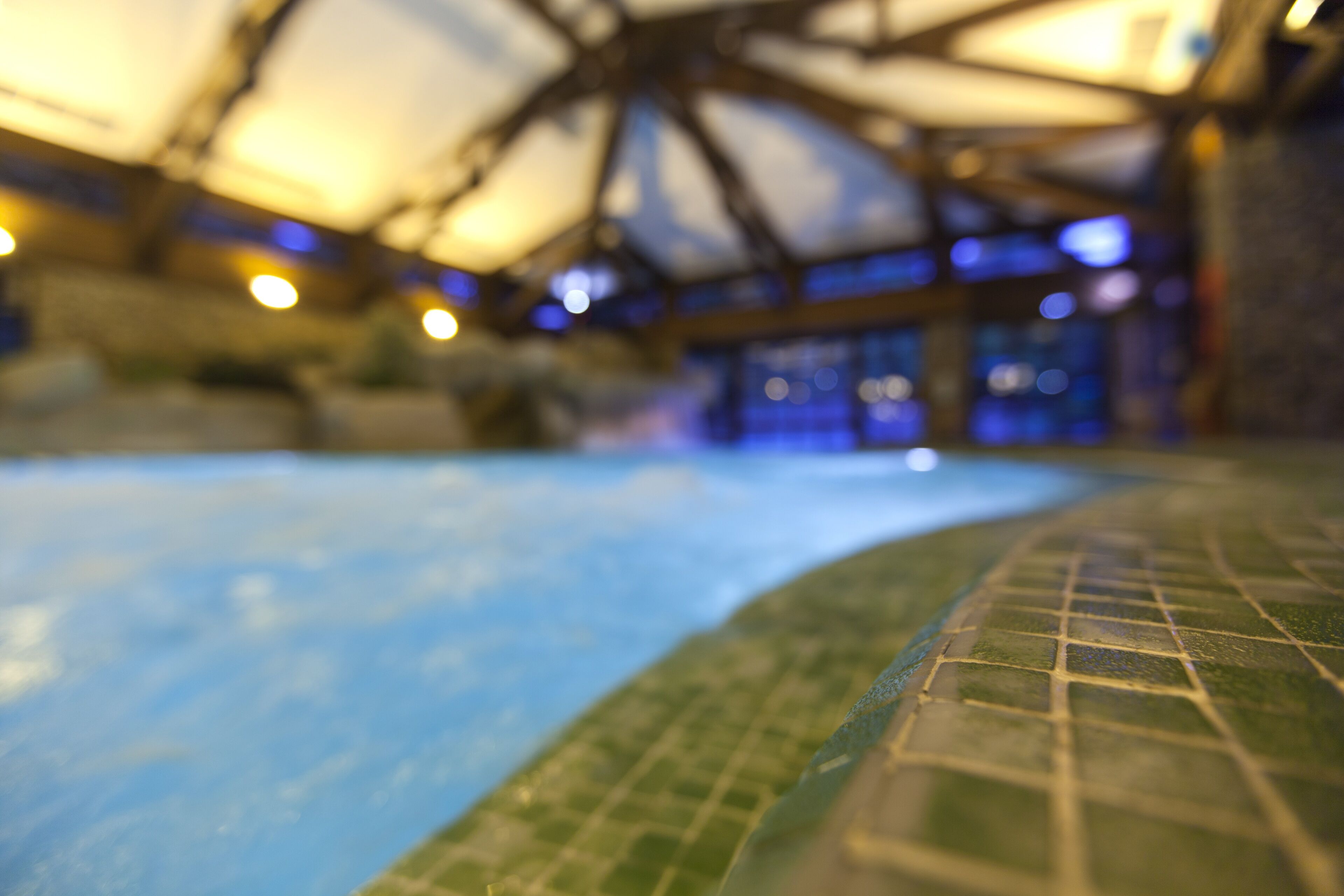 Piscina interna con bordo piastrellato e struttura coperta.