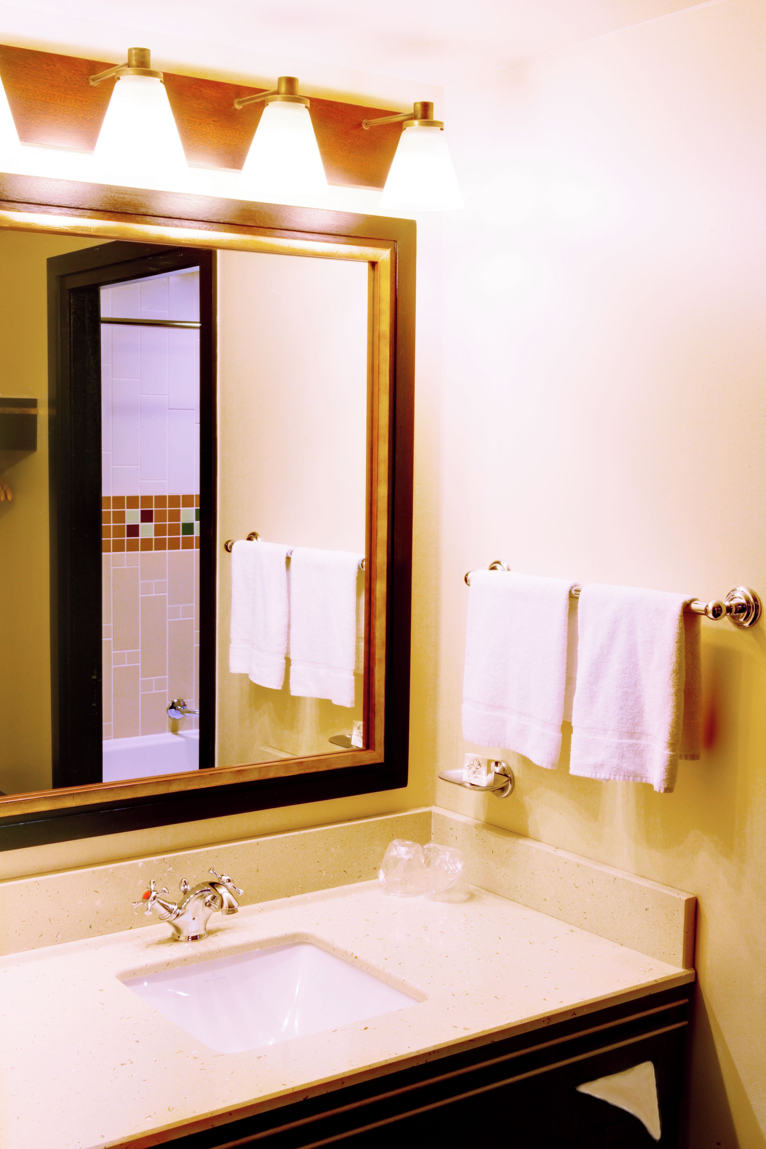 Une salle de bain avec un grand miroir, un lavabo et deux serviettes accrochées au mur.