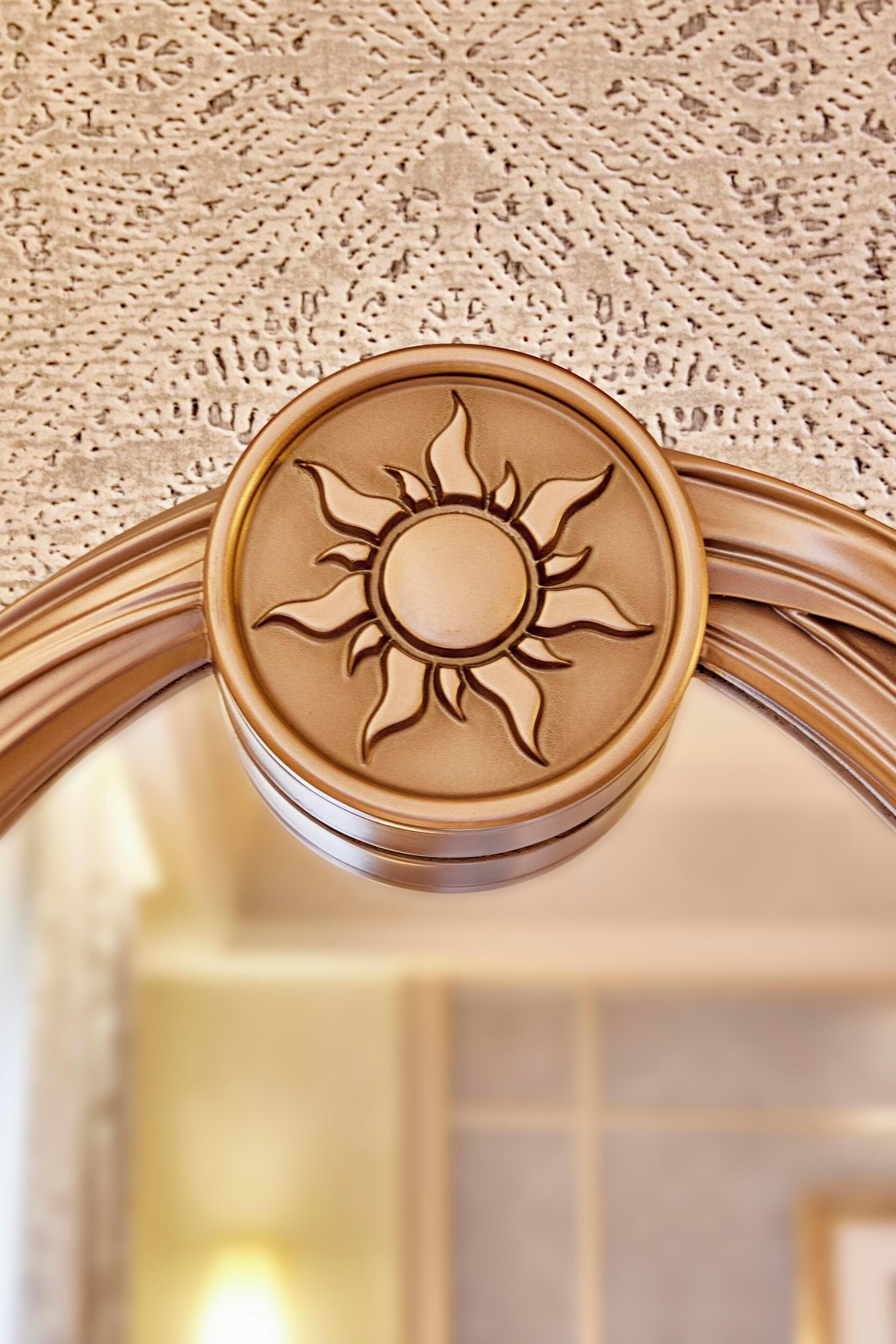 A close-up of a sun-shaped decorative element on a door frame.