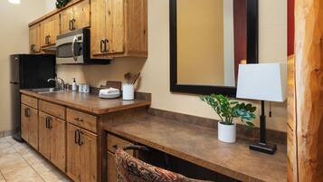 Una cocina con armarios de madera, microondas, fregadero y planta en maceta.