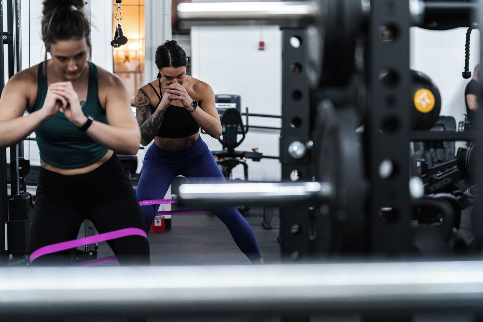 Un gimnasio con equipo de ejercicio y dos personas entrenando.