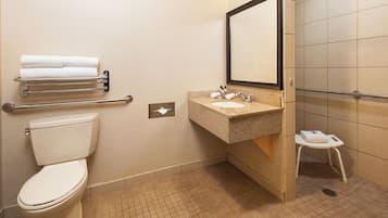 A bathroom with a toilet, sink, towel rack, and a small stool.