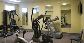 Un gimnasio con máquinas de cardio, equipo de levantamiento de pesas y espejos en las paredes.