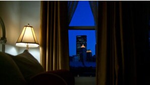 Una habitación de hotel con vista a un horizonte urbano al anochecer.