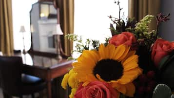 Quarto com uma escrivaninha, uma cadeira e um arranjo de flores, incluindo girassóis e rosas.