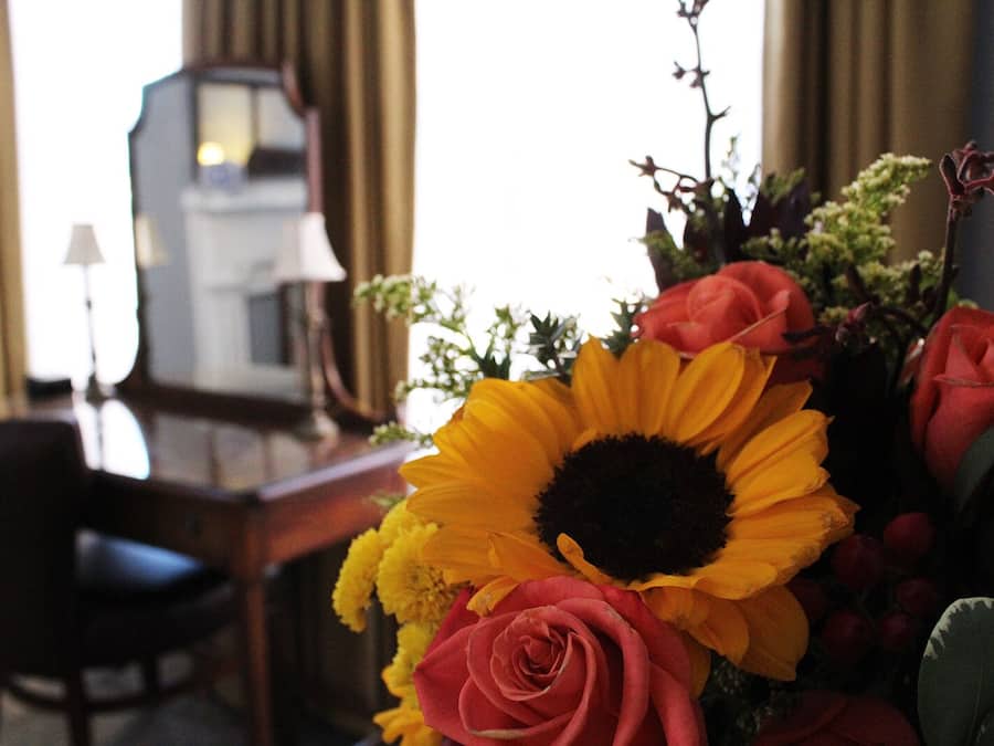 Quarto com uma escrivaninha, uma cadeira e um arranjo de flores, incluindo girassóis e rosas.