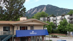 A hotel with a stone facade, a blue awning, and a mountain backdrop. - Boulder University Inn (Boulder)