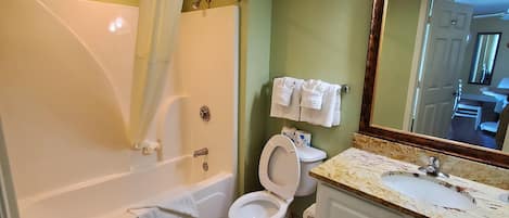 A bathroom with a bathtub, toilet, and sink.