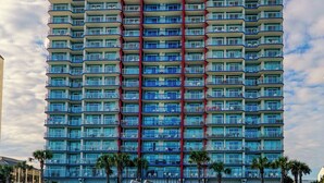 Un hôtel de grande hauteur doté de nombreux balcons, offrant une vue sur la plage et présentant une architecture moderne.